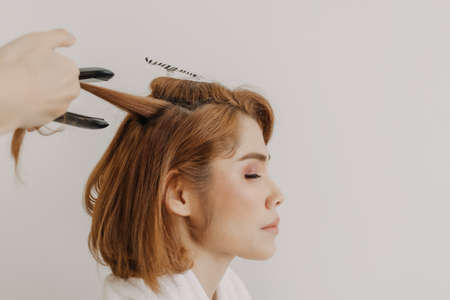 Asian woman model is dressing her hair by the hairdresser in studio room.の写真素材