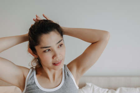Attractive Asian woman relax after wake up in bedroom. Summer vacation.の写真素材