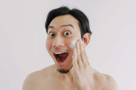 Wow and surprise face of Asian man using skin care product on his face.の写真素材