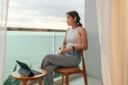 Beautiful Asian woman relax on hotel terrace with ocean view in summer.の写真素材