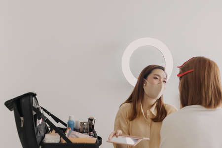 Asian woman makeup artist is at work and wearing makeup on her model.の写真素材