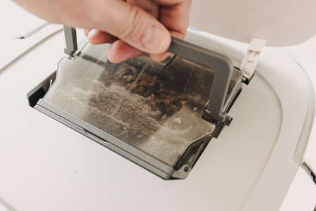 Taking off dirty dust box out of vacuum robot cleaner.
