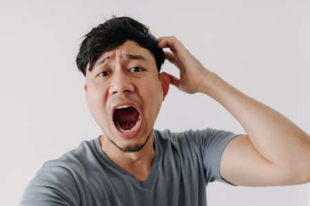 Funny face of asian man yawning isolated on white background.