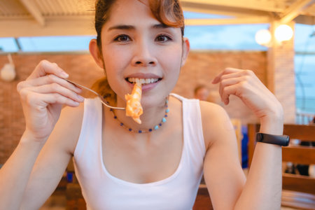 Happy Asian woman enjoy eating squid seafood in the summer vacation.の写真素材