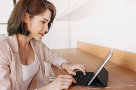 Happy Asian working woman is using a tablet in the office.の写真素材