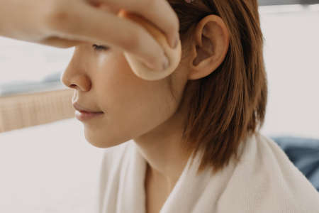 Asian woman makeup artist is at work and wearing makeup on her model.の写真素材
