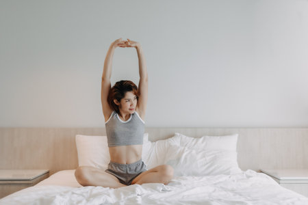 Attractive Asian woman in underwear stretching on the bed in the morning.の写真素材
