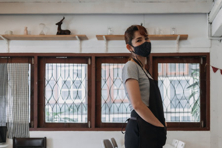 Portrait of happy Asian woman cafe and restaurant owner with face mask.の写真素材
