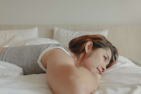 Attractive Asian woman lay on the bed feeling relax and cosy in the morning