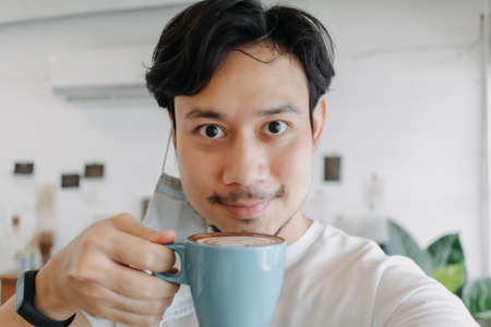 Close up of Asian man selfie himself drinks hot coffee in his house.の写真素材