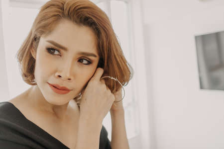 Beautiful Asian woman and her earrings in her apartment room.の写真素材