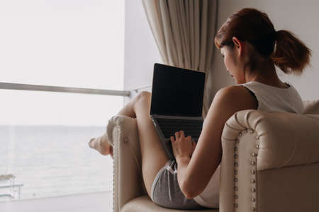Asian woman work sand relax with laptop on the sofa.