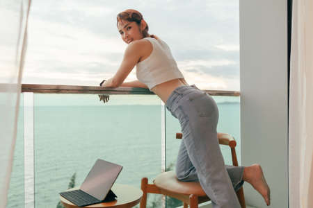 Beautiful Asian woman enjoy looking the sea view from the balcony of the hotel.