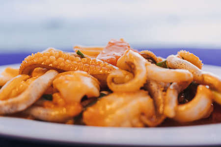 Thai Stir Fried Squid with Salted Egg Yolk served on blue table.の写真素材
