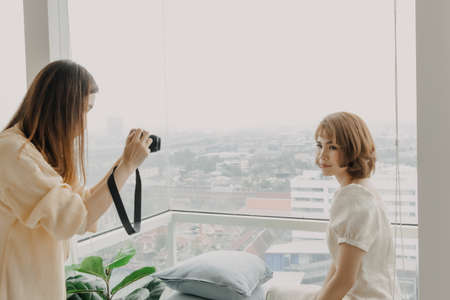 Asian woman photographer is taking a photo of her woman fashion model.の写真素材