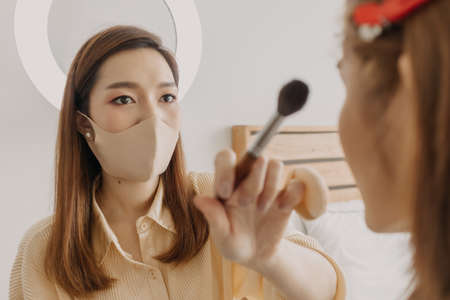 Asian woman makeup artist is at work and wearing makeup on her model.の写真素材