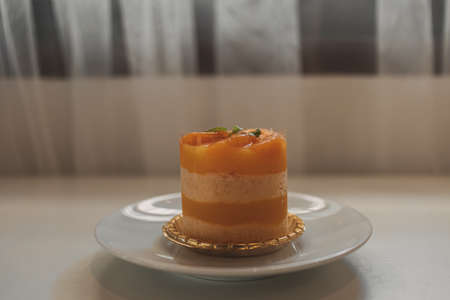 Orange fruit cake dessert in a cup served on white dish.の写真素材