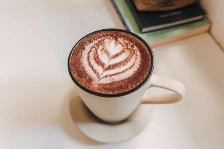 Hot latte coffee served in white mug on the table in warm morning.の写真素材