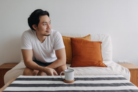Relaxed Asian man with coffee in the living room of the apartment.の写真素材