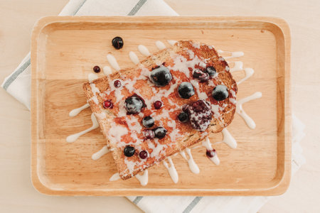 MIxed berries toast bread with condensed milk on wooden plate.
