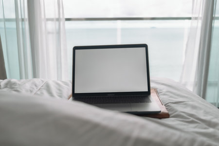 Workation concept. Empty screen laptop on bed with ocean view balcony.の写真素材