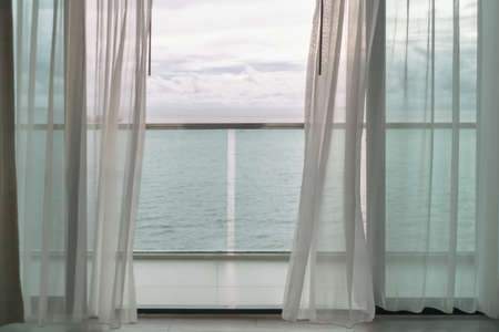 Almost evening time of ocean view from hotel balcony with curtains.の写真素材