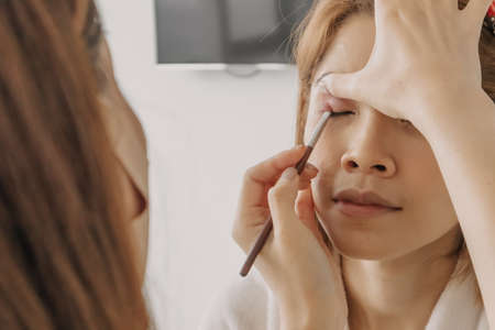 The makeup artist is applying makeup on client eyes.の写真素材