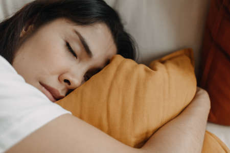 Asian woman is taking a nap or sleep on the sofa with yellow pillow.の写真素材