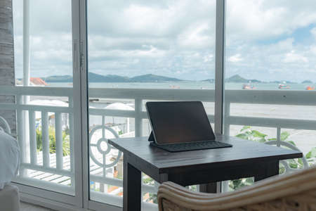 Tablet on the table at the balcony of hotel room with sea view.の写真素材