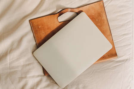Laptop with leather sleeve on beige sofa in the living room in the apartment.の写真素材