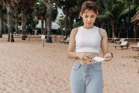 Asian woman walking on the beach with palm trees in background.の写真素材