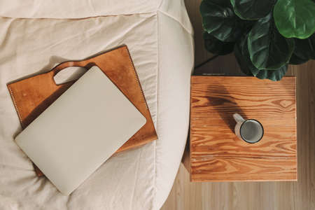 Laptop with leather sleeve on beige sofa in the living room in the apartment.の写真素材