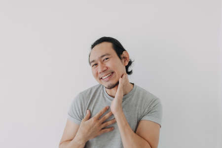 Funny cute shy Asian man in grey t-shirt on isolated white background.の写真素材