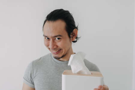 Funny smile face of Asian man holding tissue in concept of self satisfied.の写真素材