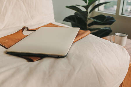 Laptop with leather sleeve on beige sofa in the living room in the apartment.の写真素材