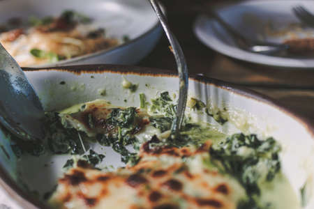 Close up of eaten Baked Spinach with Cheese served in small bowl.