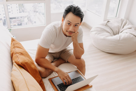 Happy smiling Asian man working in his apartment in concept work from home.の写真素材