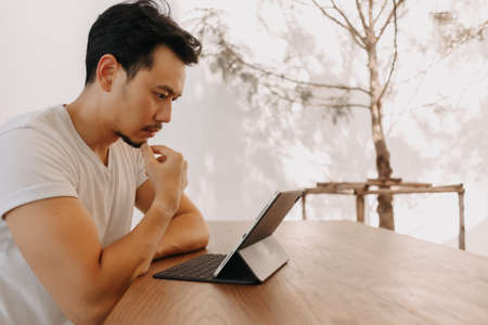 Freelance Asian man is working with concentrate on his tablet in the cafe.の写真素材
