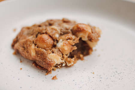 Close up of bitten homemade soft cookie on white plate.