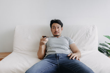 Asian bored man check out the tv but nothing is interesting.の写真素材