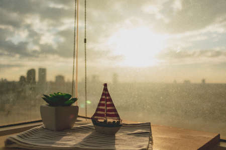 Sailboat and plant on the table with cityscape. Concept of vacation and work.の写真素材