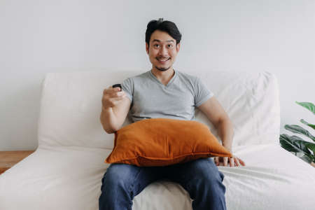 Excited face of asian man watching tv channel in his living room.