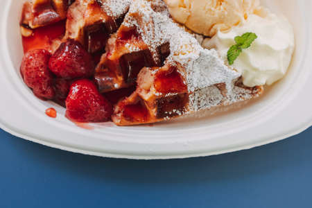 Dessert set of ice-cream waffle with cherries served on blue table.の写真素材