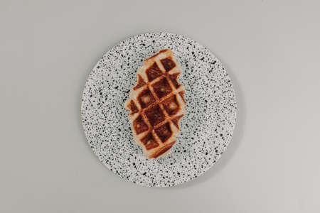 Close up small piece of homemade waffle on white dots dish.