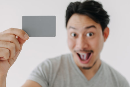 Happy funny face Asian man show off his empty card on white background.の写真素材