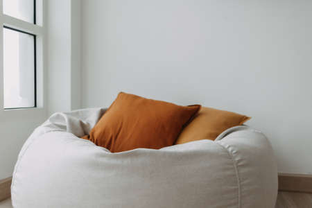 Brown pillows and beanbag sofa in white room next to the windowの写真素材