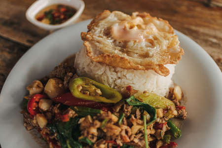 Thai Rice topped with stir-fried minced beef basil and fried egg on white dish.の写真素材