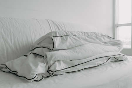 Fold sofa bed with white pillow and blanket ready to be clean up in the morning.