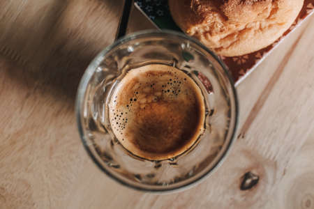 Two espresso coffee and eclair on wooden table in the morning light.の写真素材