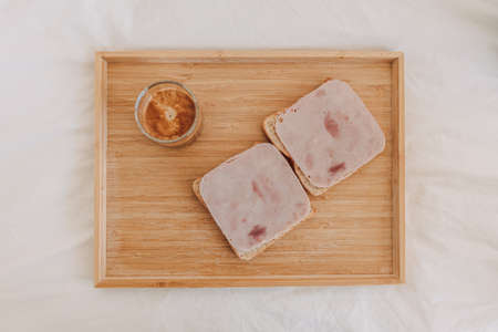Top view of sandwich ham with espresso coffee served on white bed.
